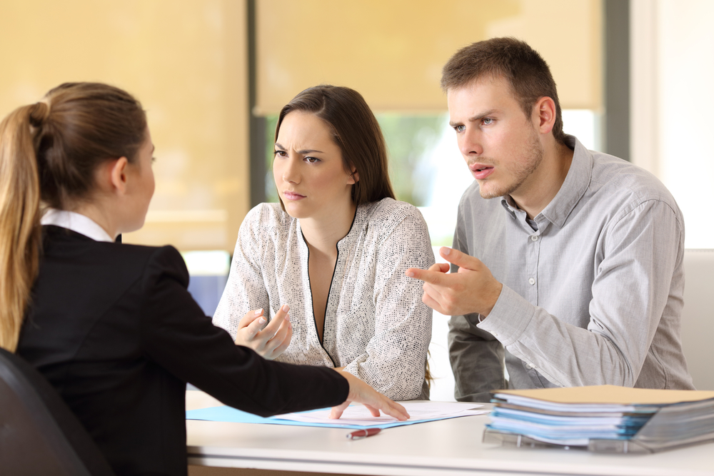 angry couple claiming to a businesswoman at office